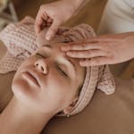 Woman enjoying a soothing facial massage with gua sha tool, promoting relaxation and skin care.